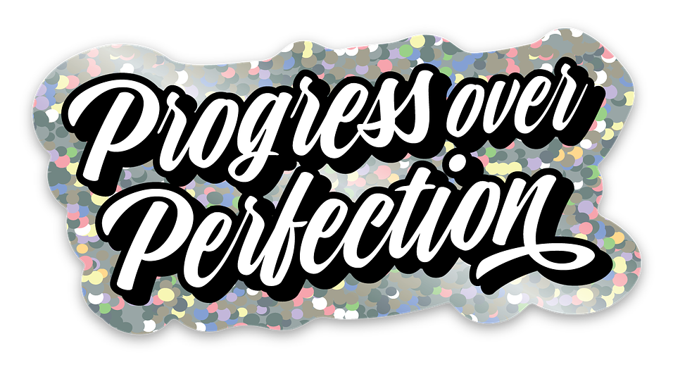 Die cut glitter sticker with the words “Progress over Perfection” in an elegant brush script font. White letters with a black outline and shadow.